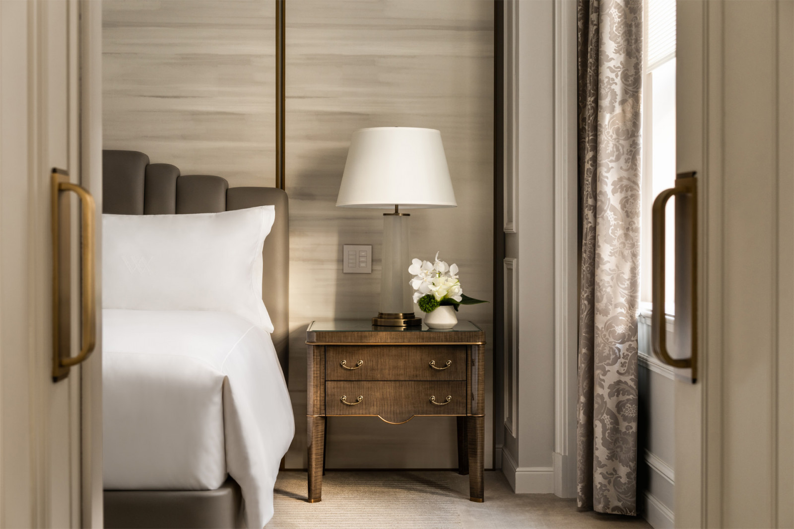 Suite bedrooms feature custom millwork, upholstered headboards, and separate sleeping zones, in keeping with the film hotel’s contemporary luxury standards