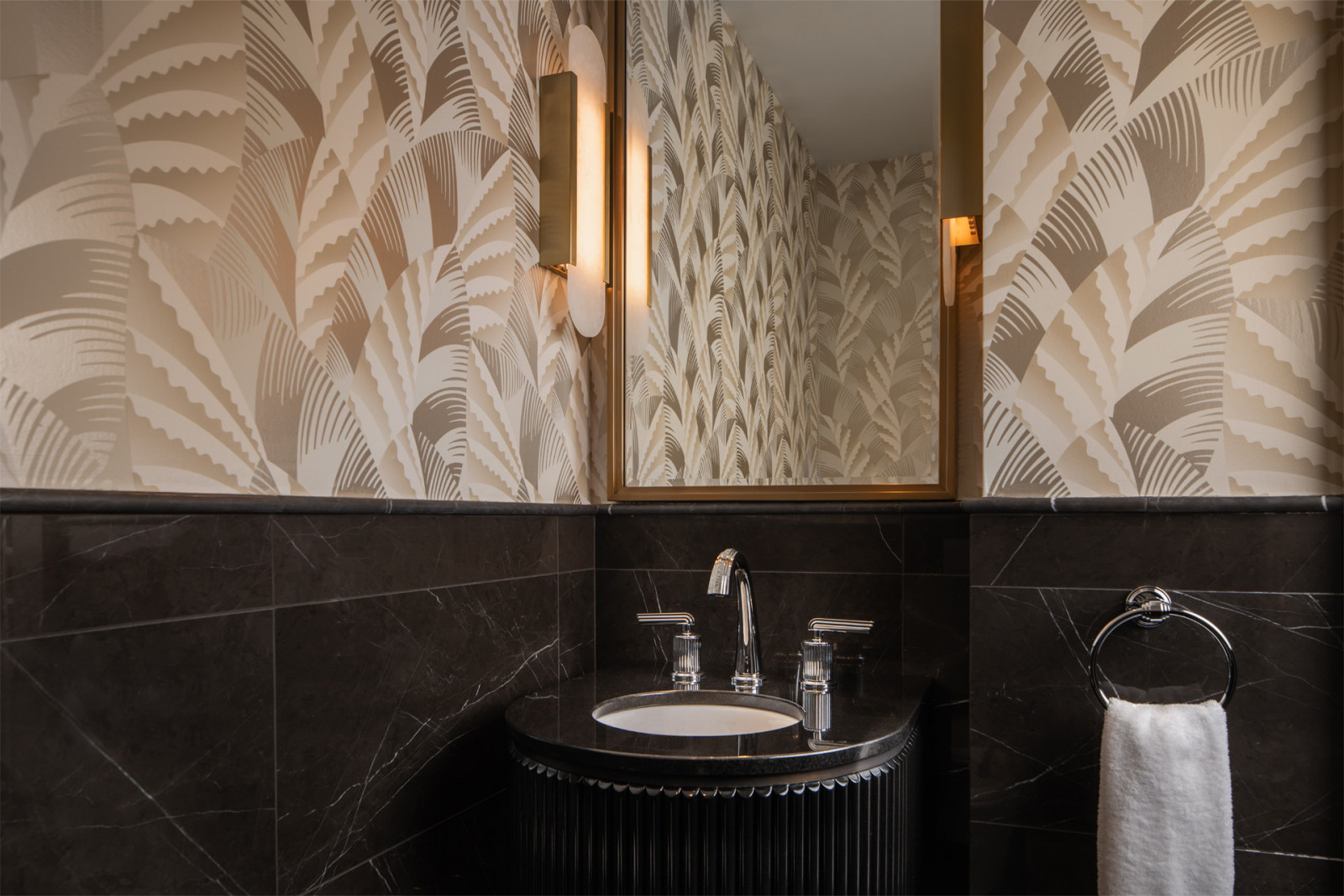 Powder rooms combine Art Deco palm-leaf wallpaper with black marble and brass fixtures, balancing historic motifs with modern comfort
