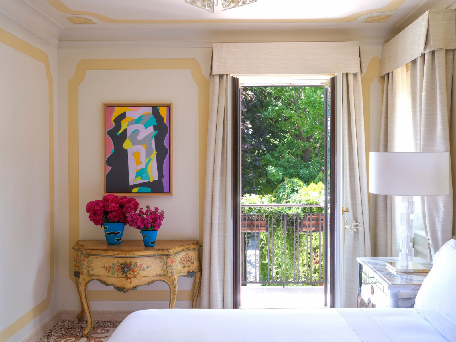 Garden-facing bedrooms feature antique Venetian commodes and contemporary art, with private terraces overlooking the Giudecca Island gardens where film stars retreat during the Venice Film Festival