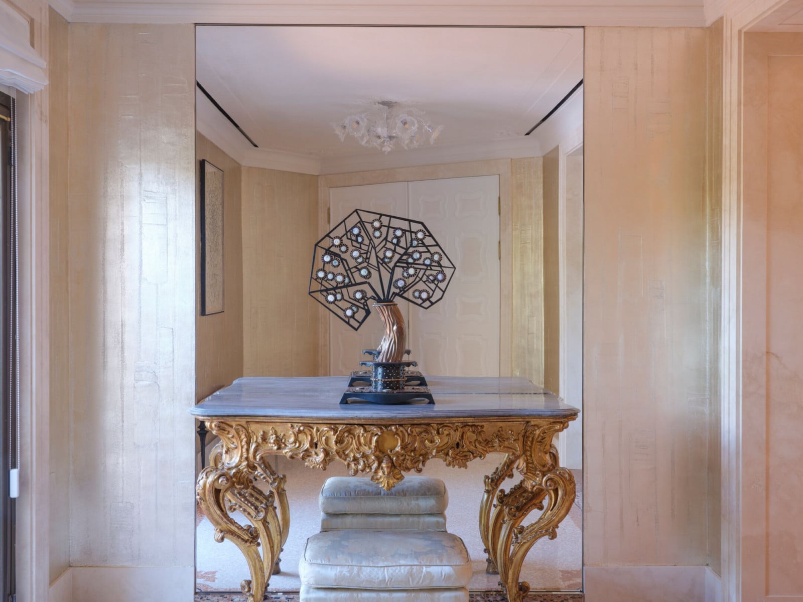 Gilt Baroque consoles juxtapose with contemporary bronze sculptures in suite foyers, exemplifying Marino’s multi-layered design approach