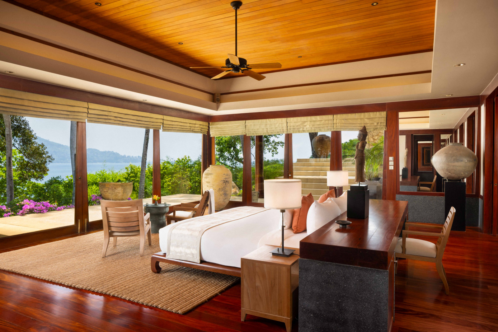 The Deluxe Ocean View bedroom opens towards the sea, with a study positioned behind the bed that also takes in the view