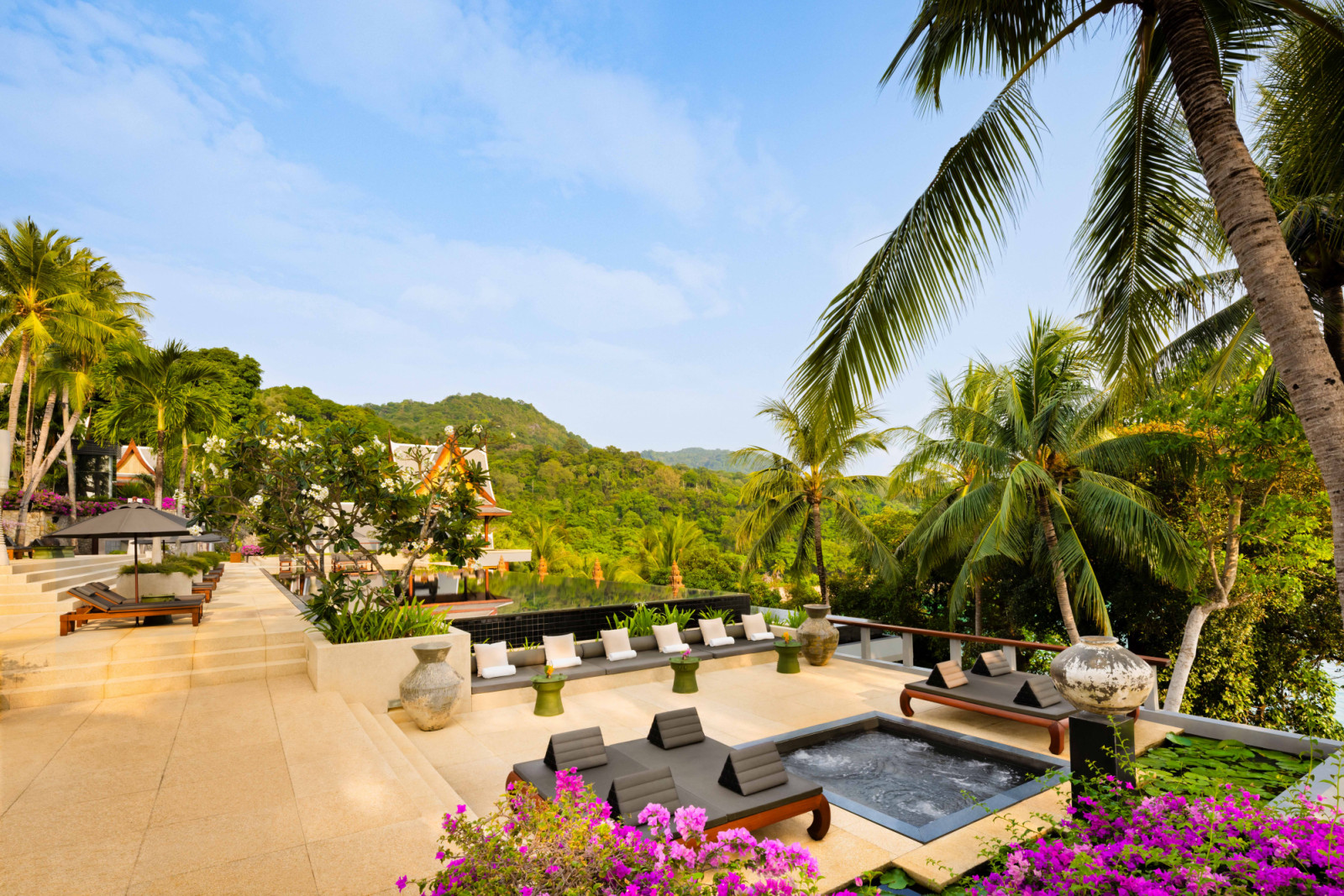 A large sunken outdoor living area softened by generous daybeds and a plunge pool with built-in water jets, set amid palms