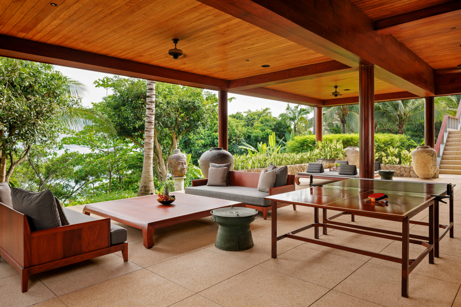 Tucked at the side of the site, a terrace with table tennis, generous proportions and ample seating areas, set within a covered area overlooking the landscape