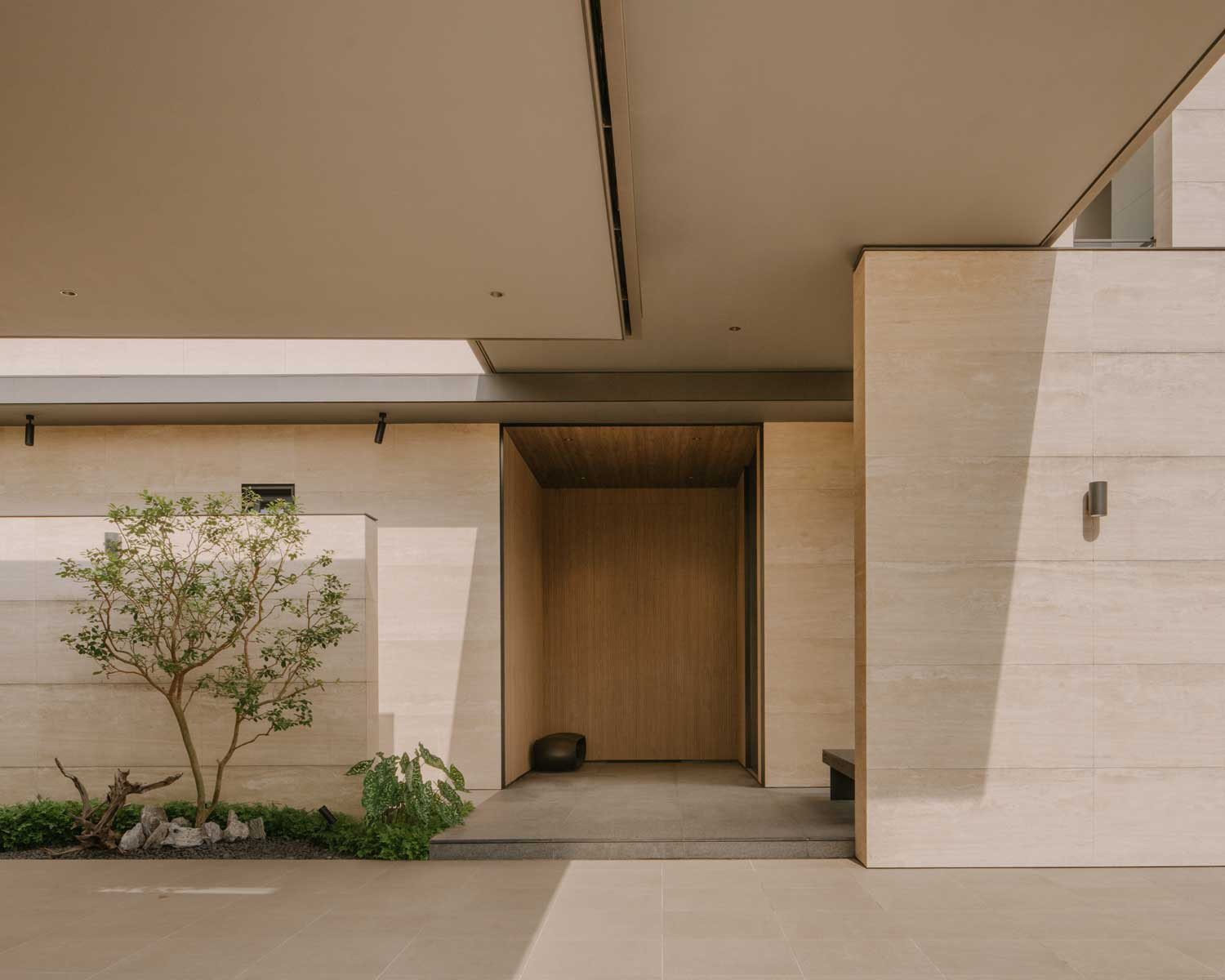 The travertine-clad main opening of the home is layered, letting light and shadow play and shift across surfaces throughout the day