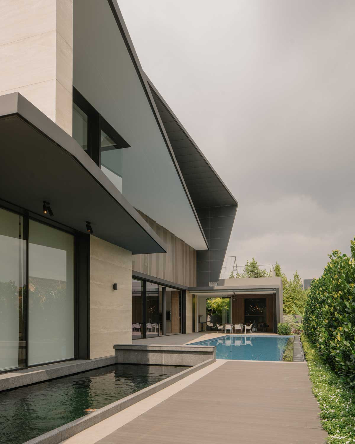 The dining pavilion, pool and garden in the day, together with the dynamic slanted roof uniting facade and back wall