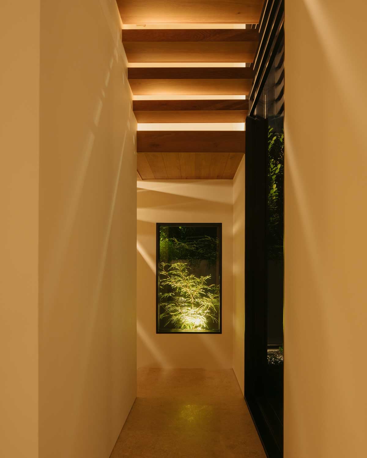 A light-dappled corridor leading to the staircase down to the basement entertainment room