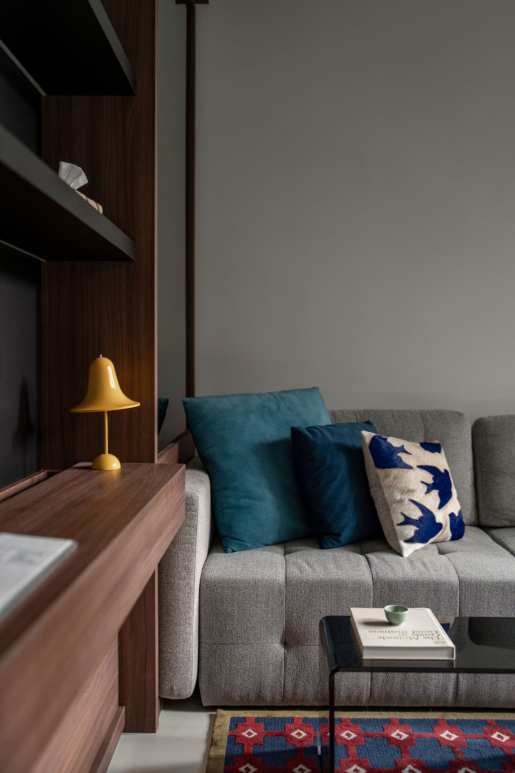 The ground floor living area features custom upholstered seating and black louvres that frame views to the garden