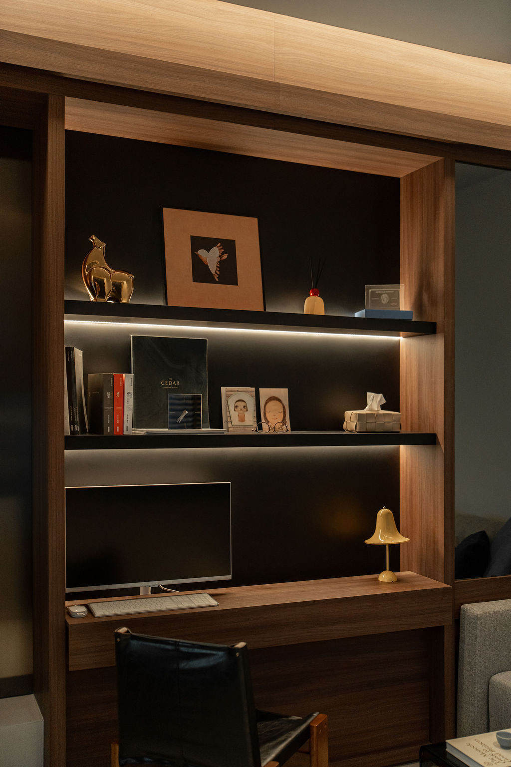 Built-in shelving in the first-floor study features integrated LED lighting and black backing panels within walnut framing