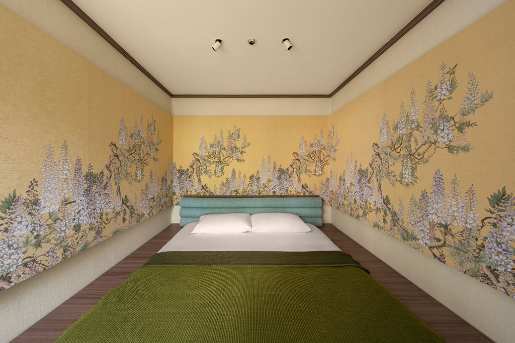 The master bedroom’s sunken platform is framed with botanical wallpaper and padded surfaces, creating an intimate enclosure