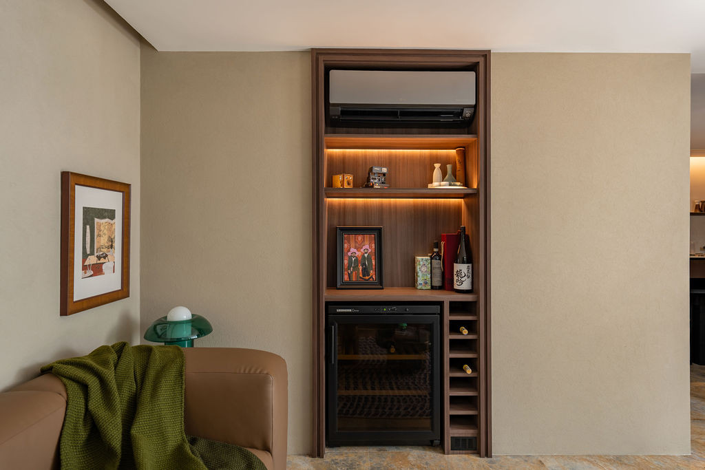 Custom walnut joinery integrates wine storage and display shelving within the living area, with warm integrated lighting.