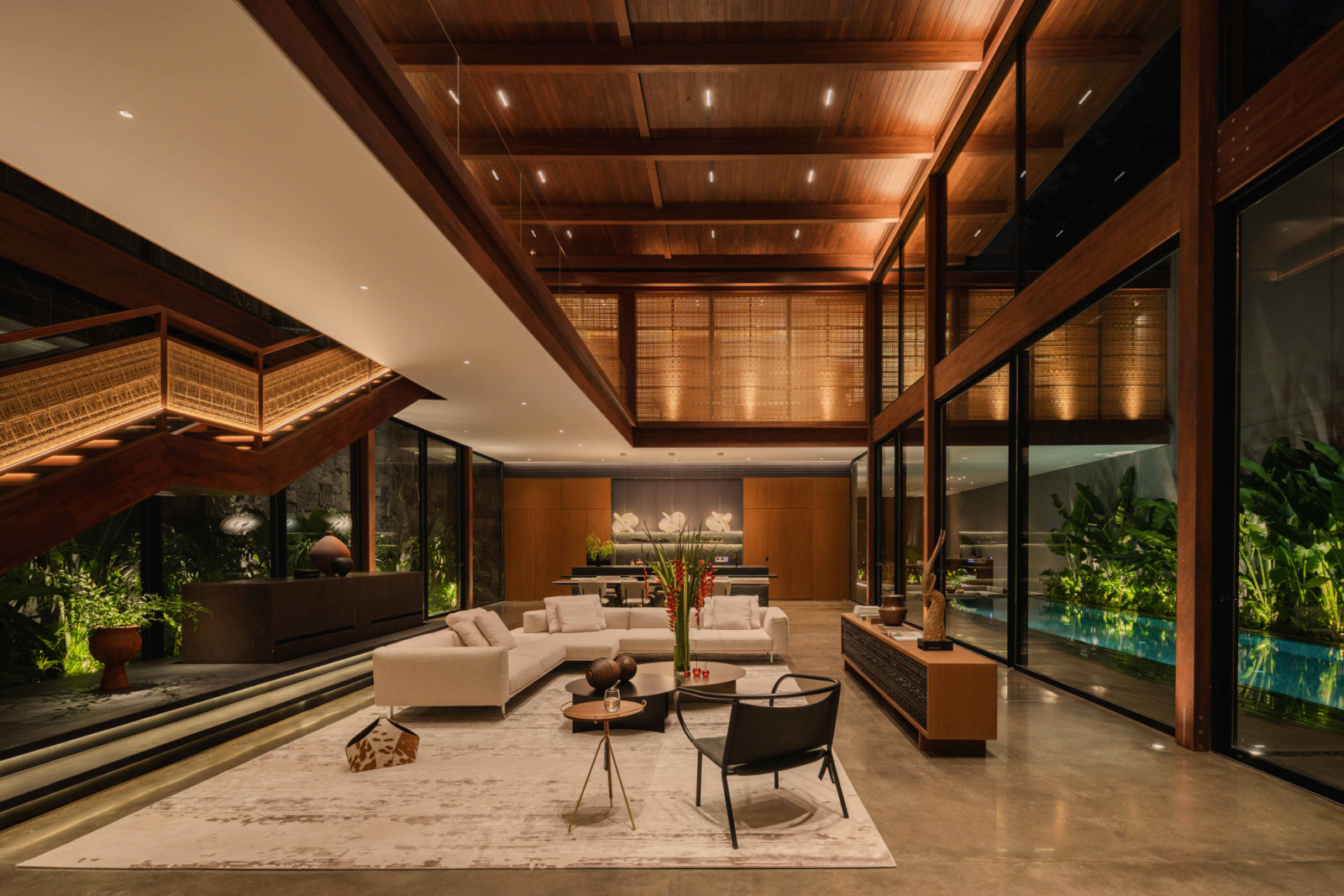 The double-volume living room is made column-free by a 14-metre local glulam beam, with rattan panels by Byo Living softening the space