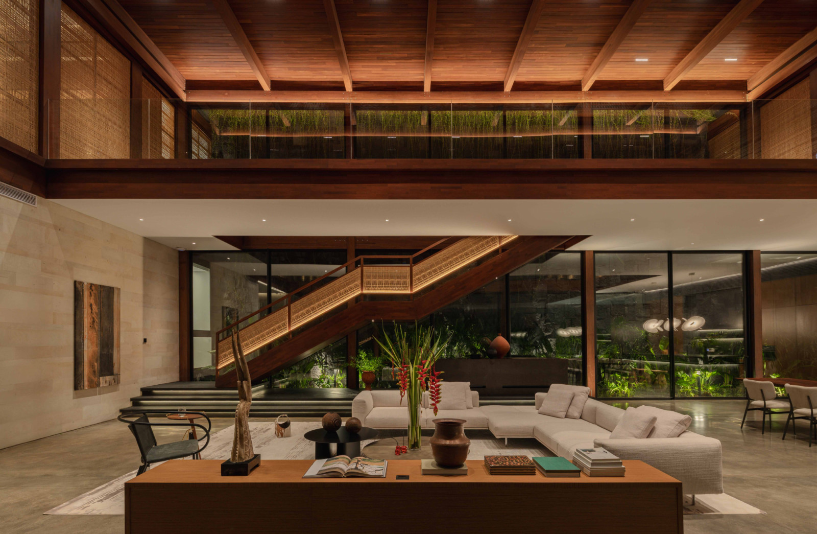 The Intertwined Residence’s double-height communal living room is defined by a timber ceiling and rattan panels wrapping the staircase, forming a column-free core