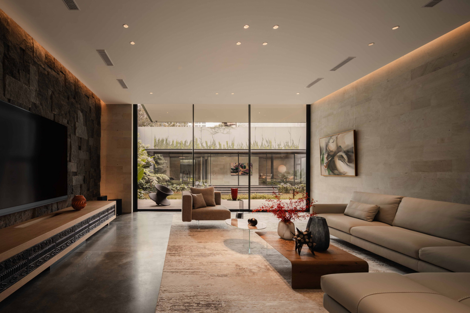 From the living room, the Intertwined Residence’s backyard gallery and gym is framed through full-height glazing, reinforcing the home’s visual continuity