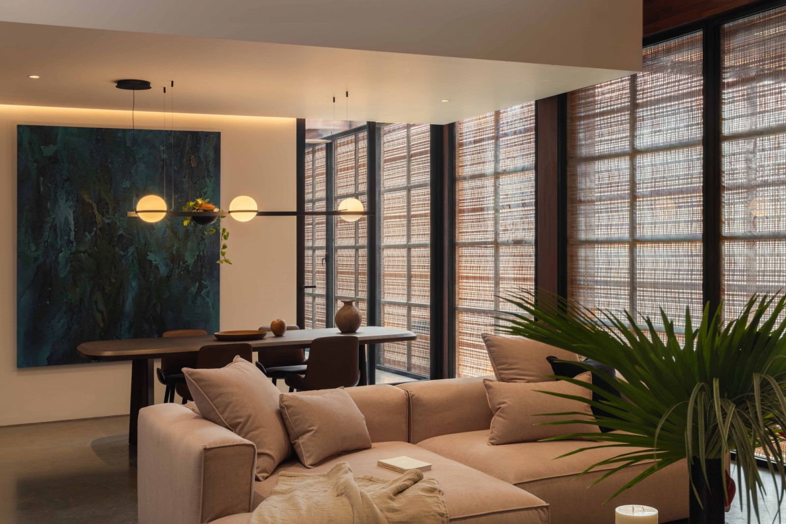A smaller dining and living area is defined by woven screens, which filter the light while maintaining privacy