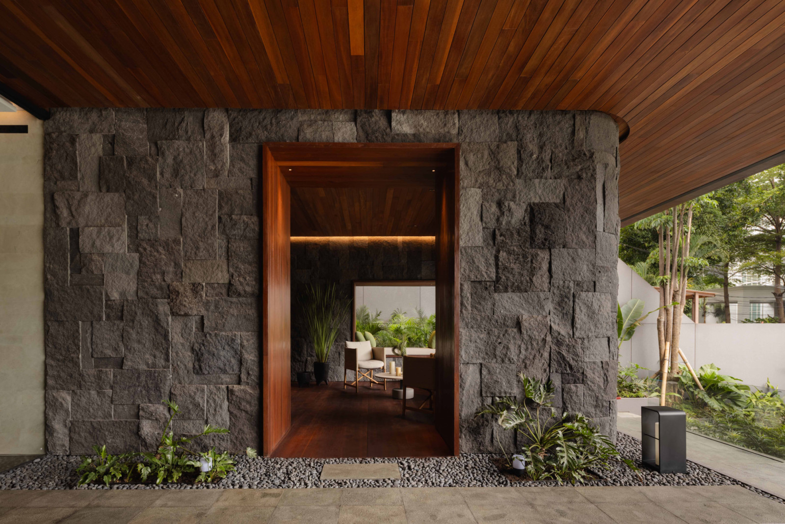 A stone-clad entry portal framed by a timber lining marks the transition from garden to interior