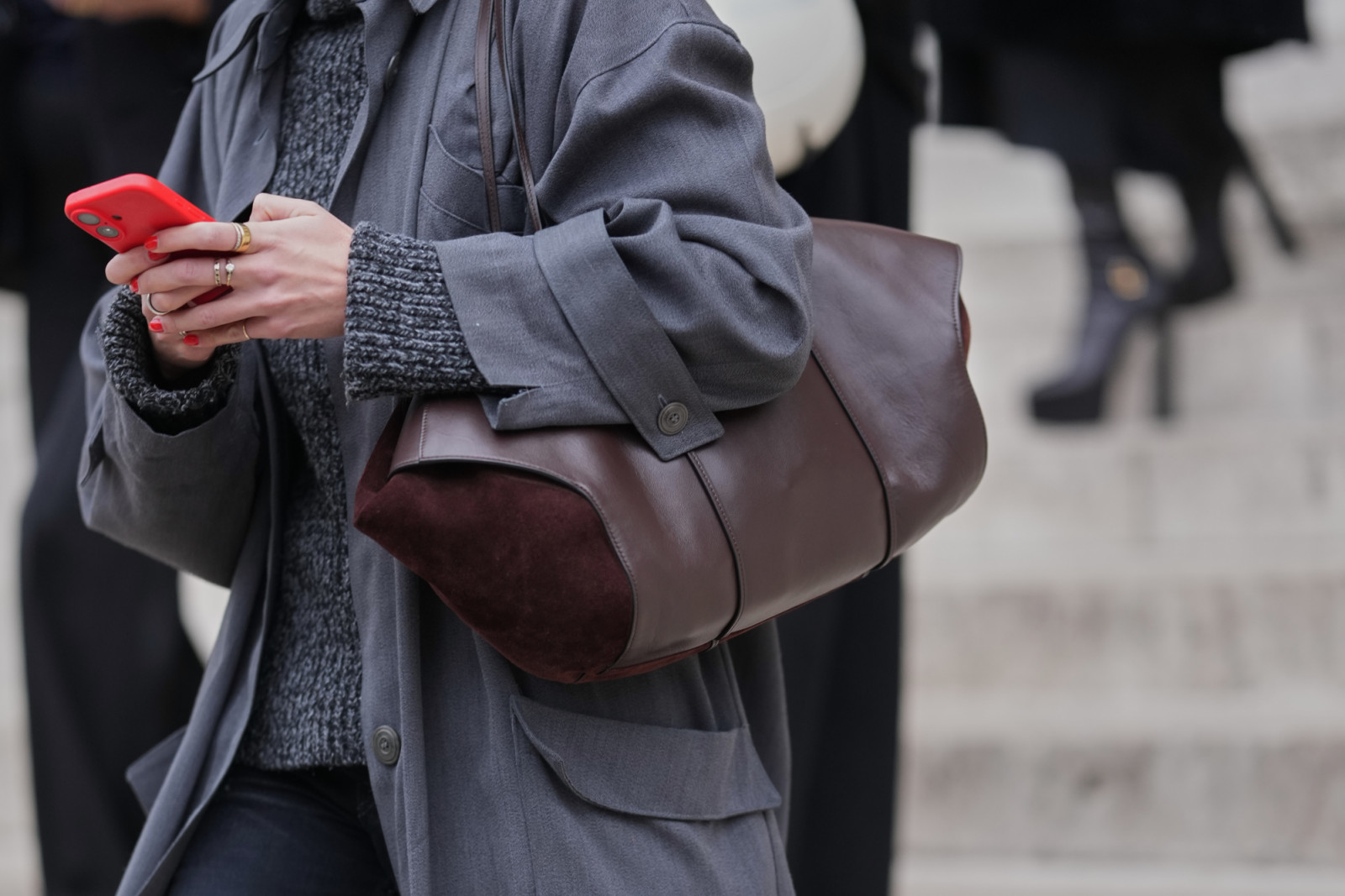PARIS, FRANCE - JANUARY 29: A guest wears a dark brown leather and suede shoulder bag, a gray charcoal long coat with a wide collar and large patch pockets, a gray charcoal rib knit high-neck / turtleneck sweater with matching rib knit cuffs, outside Ashi Studio, during Paris Fashion Week - Haute Couture - Spring Summer 2026, on January 29, 2026 in Paris, France (Photo by Edward Berthelot/Getty Images)