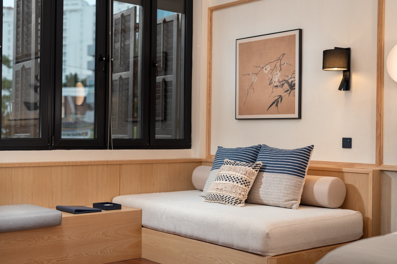 Signature Suite reading nook with a built-in daybed and timber joinery, with black timber-framed windows overlooking the Blue Mansion across Leith Street