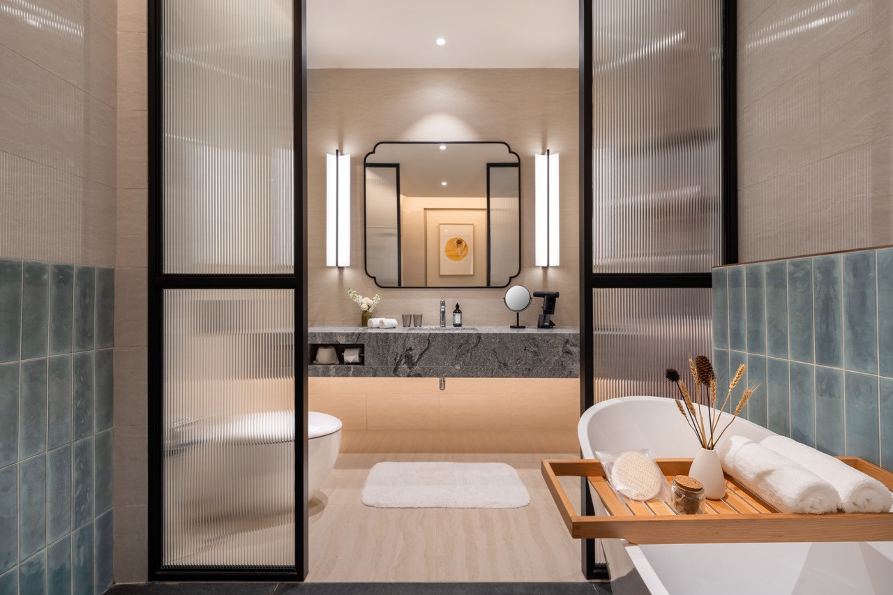 A Signature Suite bathroom with custom tilework, marble vanity and freestanding tub