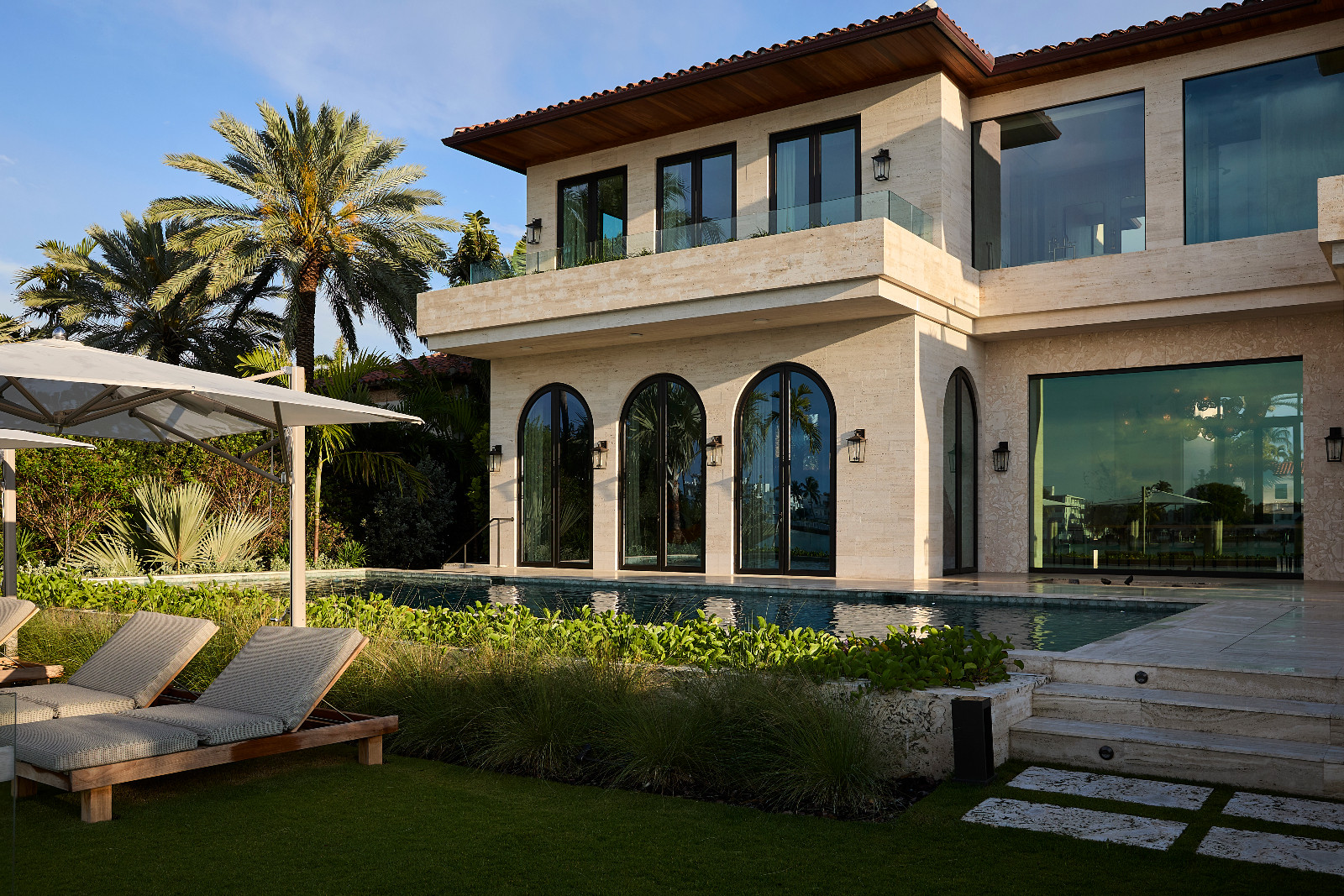 The pool area and exterior of a waterfront Miami Beach home designed by Strang Architects with Pembrooke + Ives