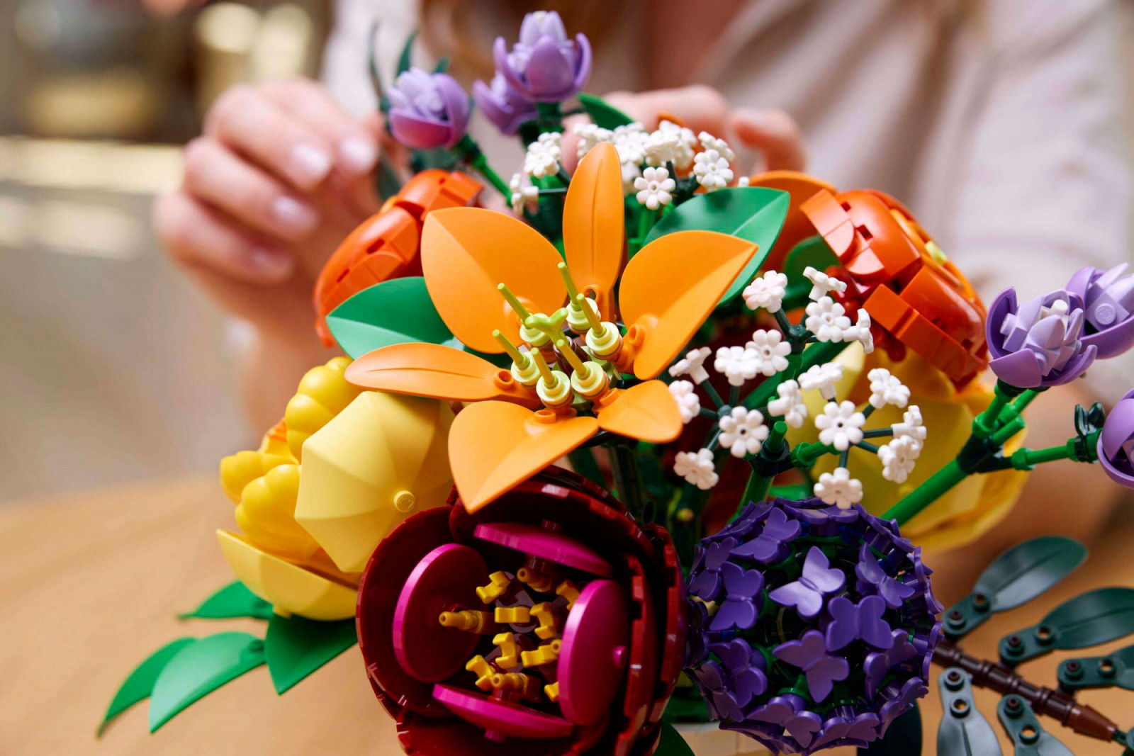 Close detail of the camellia construction in orange, with the ranunculus in yellow alongside. The camellia uses concentric rings of curved brick pieces to replicate the flower’s spiral petal formation, a technique that requires no specialised elements