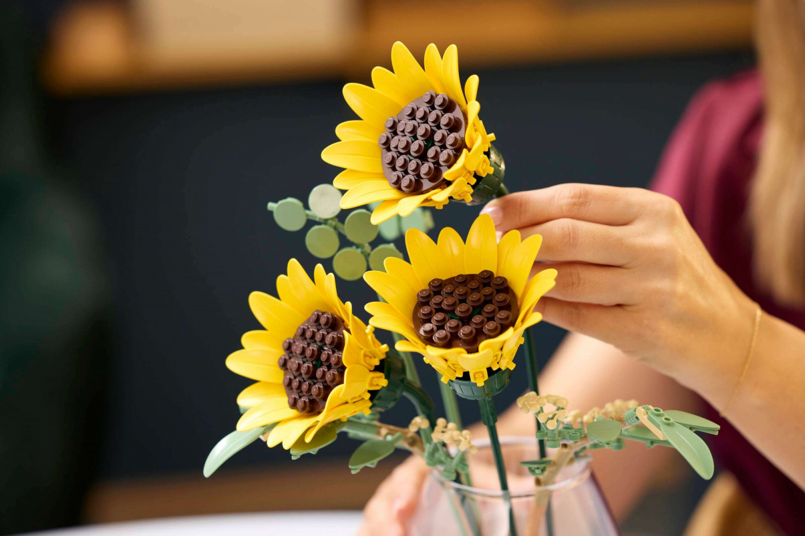 The dark brown seed head is built from a studded base plate with stud-topped round pieces arranged across its surface to replicate the packed seed pattern of a real sunflower