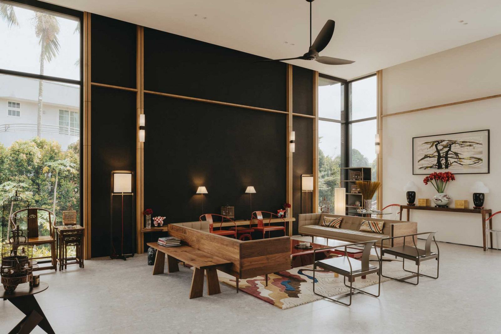 The red-finished furniture pieces at the centre of Good Class Bungalow’s second-floor living room create a striking contrast against the black wall