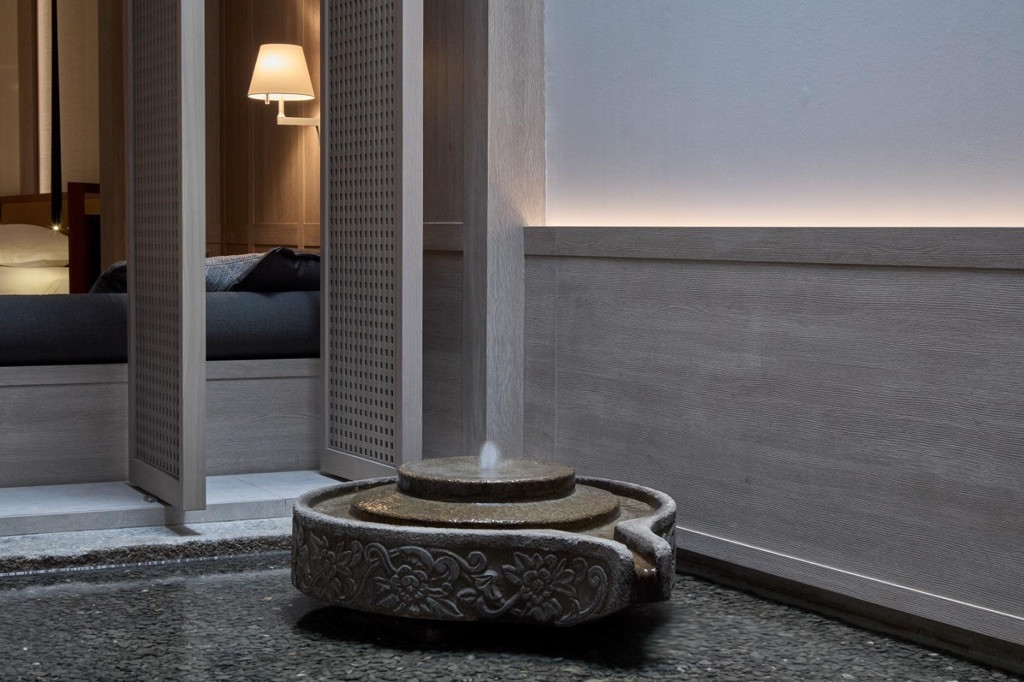 A reinterpreted rice grinder repurposed as a water fountain in the suite airwell, one of several Peranakan references Chan translated into contemporary form, rather than a literal reproduction