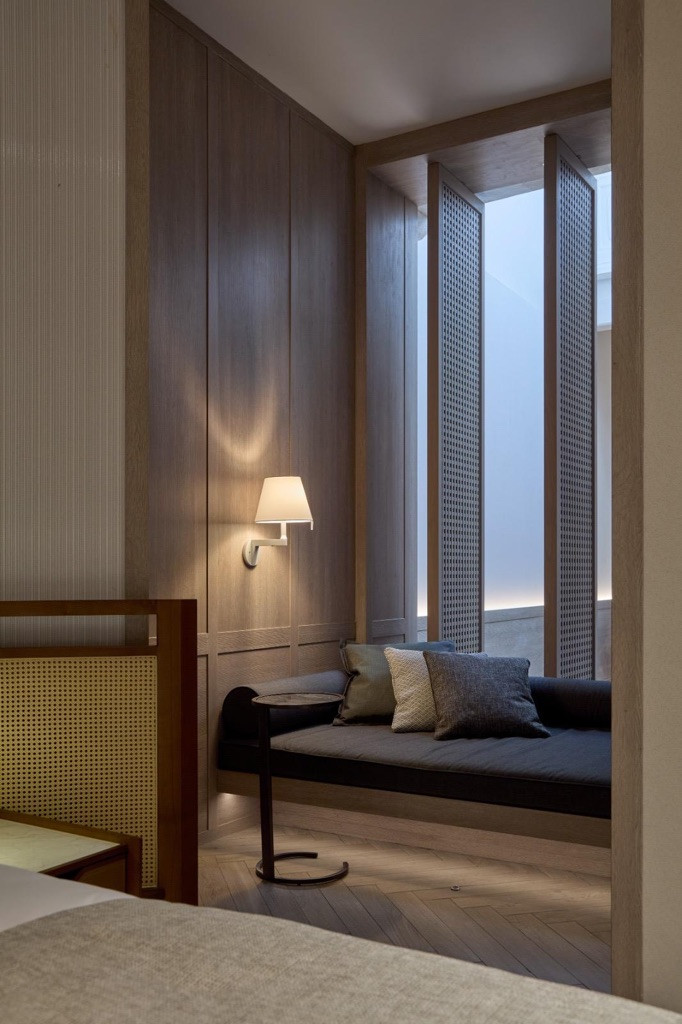 A daybed positioned toward the airwell, where natural light filters through cane screens, capturing the indoor-outdoor quality Chan describes as central to his design philosophy