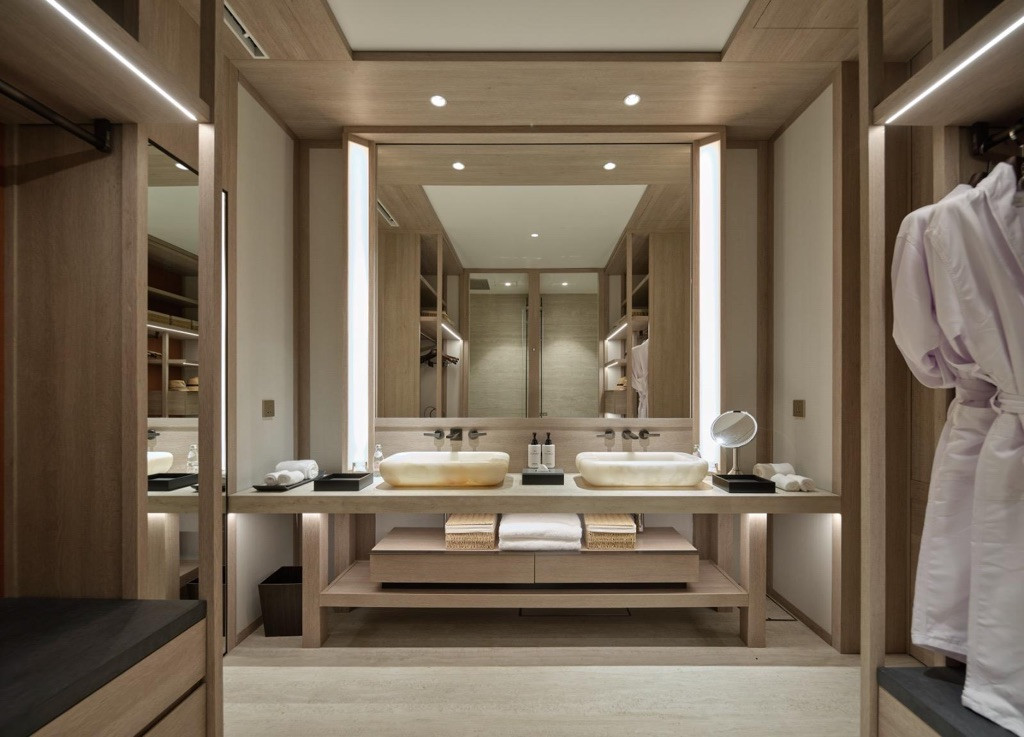 The bathrooms continue the elegant palette of the suites, with stone vessel basins and warm timber joinery that echo the quiet material order of the spaces throughout
