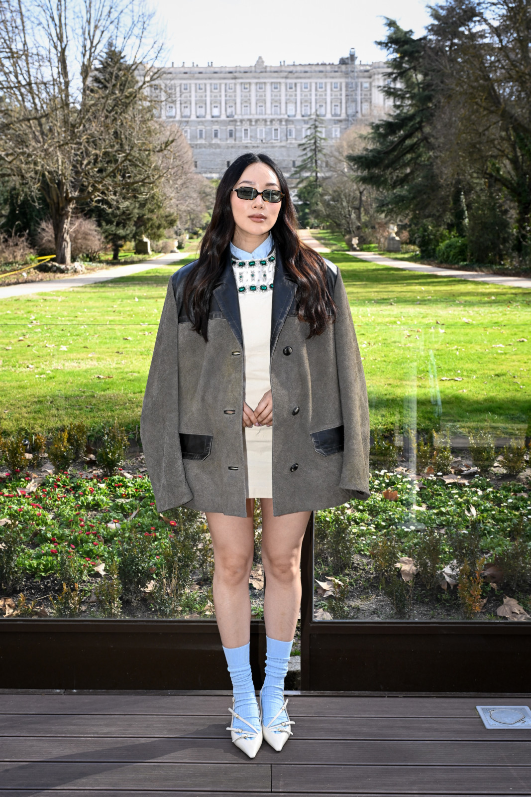 Yerin Ha pairs a Miu Miu embellished mini with an oversized coat for a modern city look (Photo by Carlos Alvarez/Getty Images for Netflix)