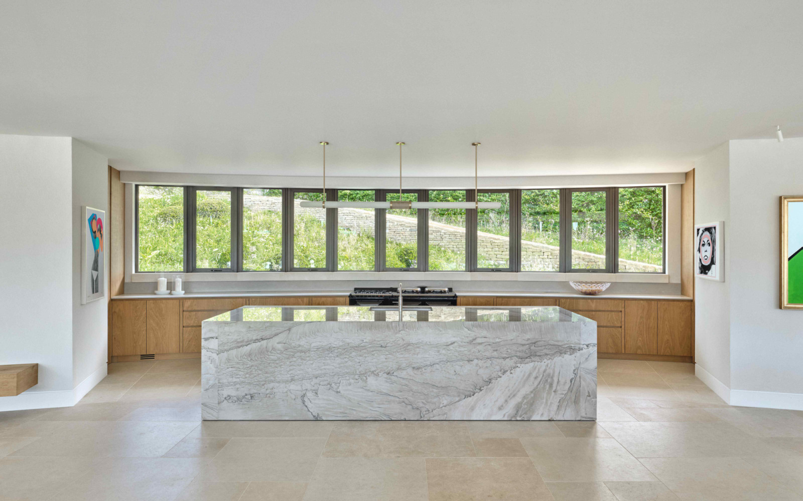 The kitchen with a curved back wall, and an anchoring marble island with dramatic veining