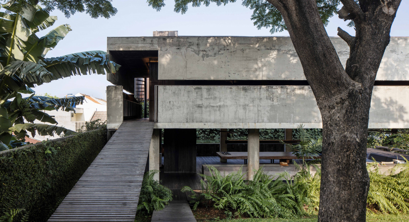 The exterior view of the AM House reveals an open-air dining space on the ground floor and an ironwood ramp that connects the different volumes and levels of the home. (Photo by Davy Linggar)
