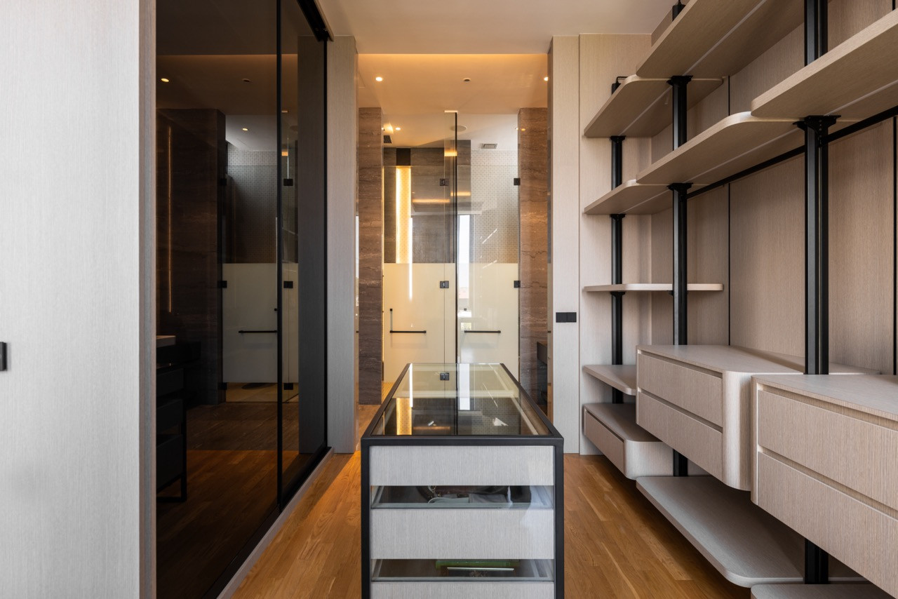 The master walk-in wardrobe, showing the central glass-topped jewellery display unit, open timber shelving on black steel rails