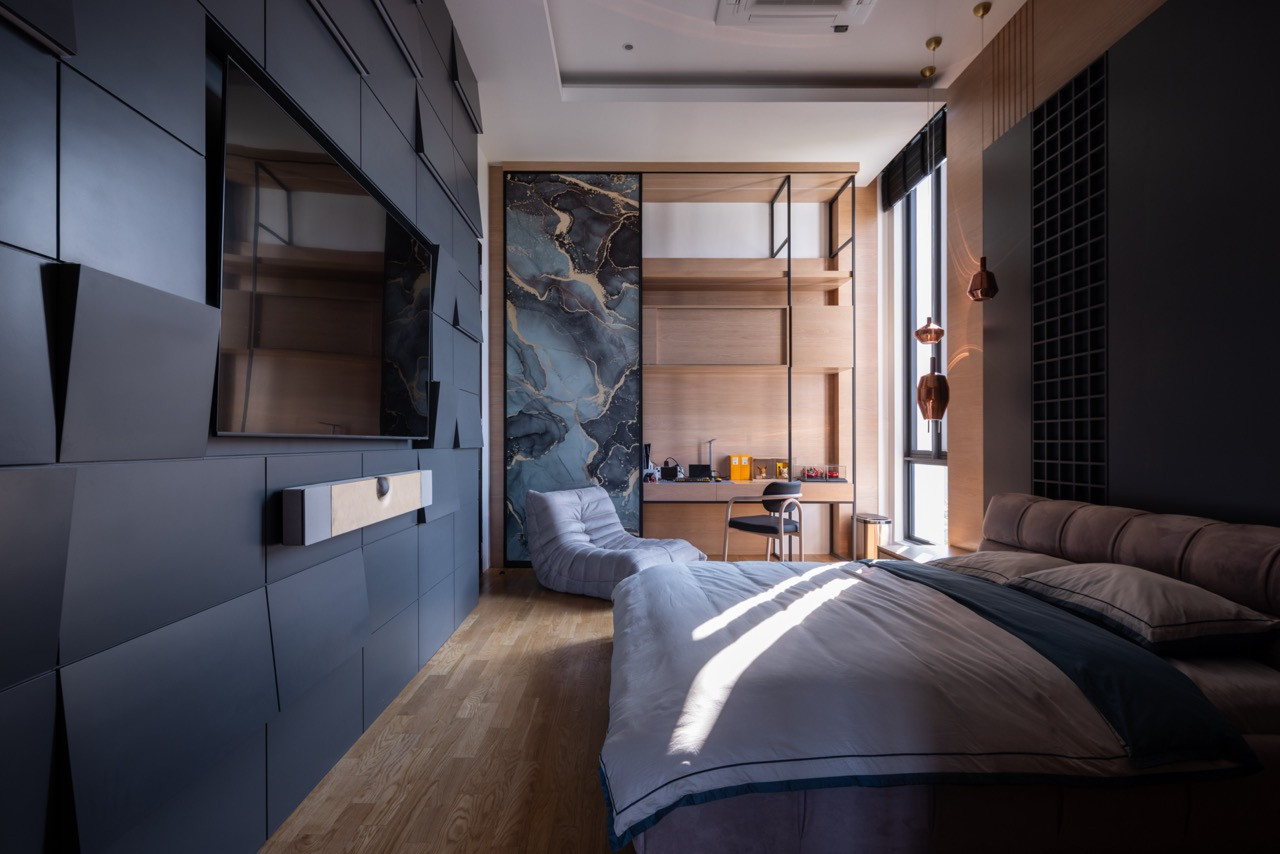 The same bedroom suite viewed from the opposite end, with a study nook behind a sliding panel of dark marble, open timber shelving and copper pendant lights to the right