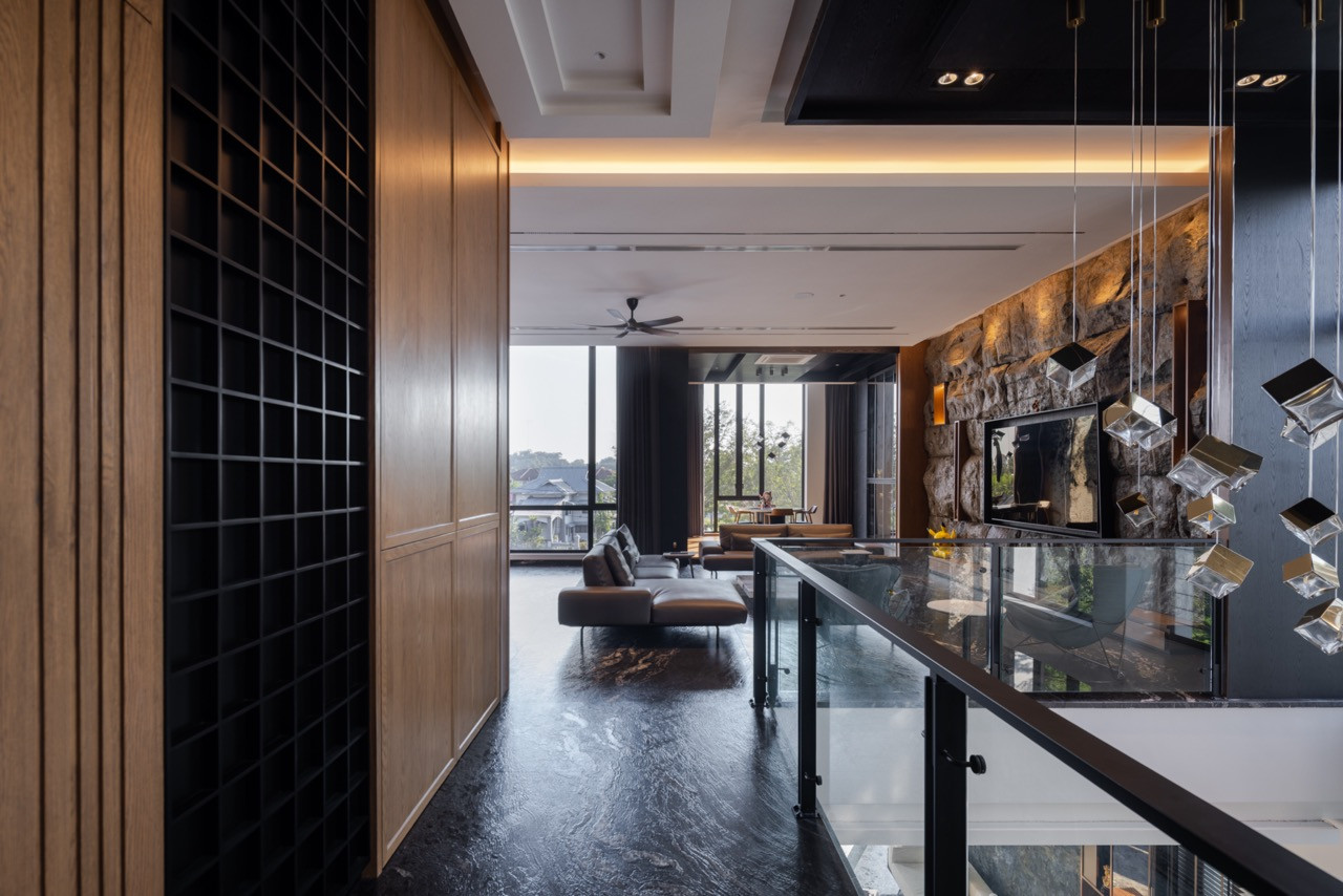 Looking along the upper-level landing toward the living room, with the gridded timber joinery to the left and the geometric pendant fixture in the foreground