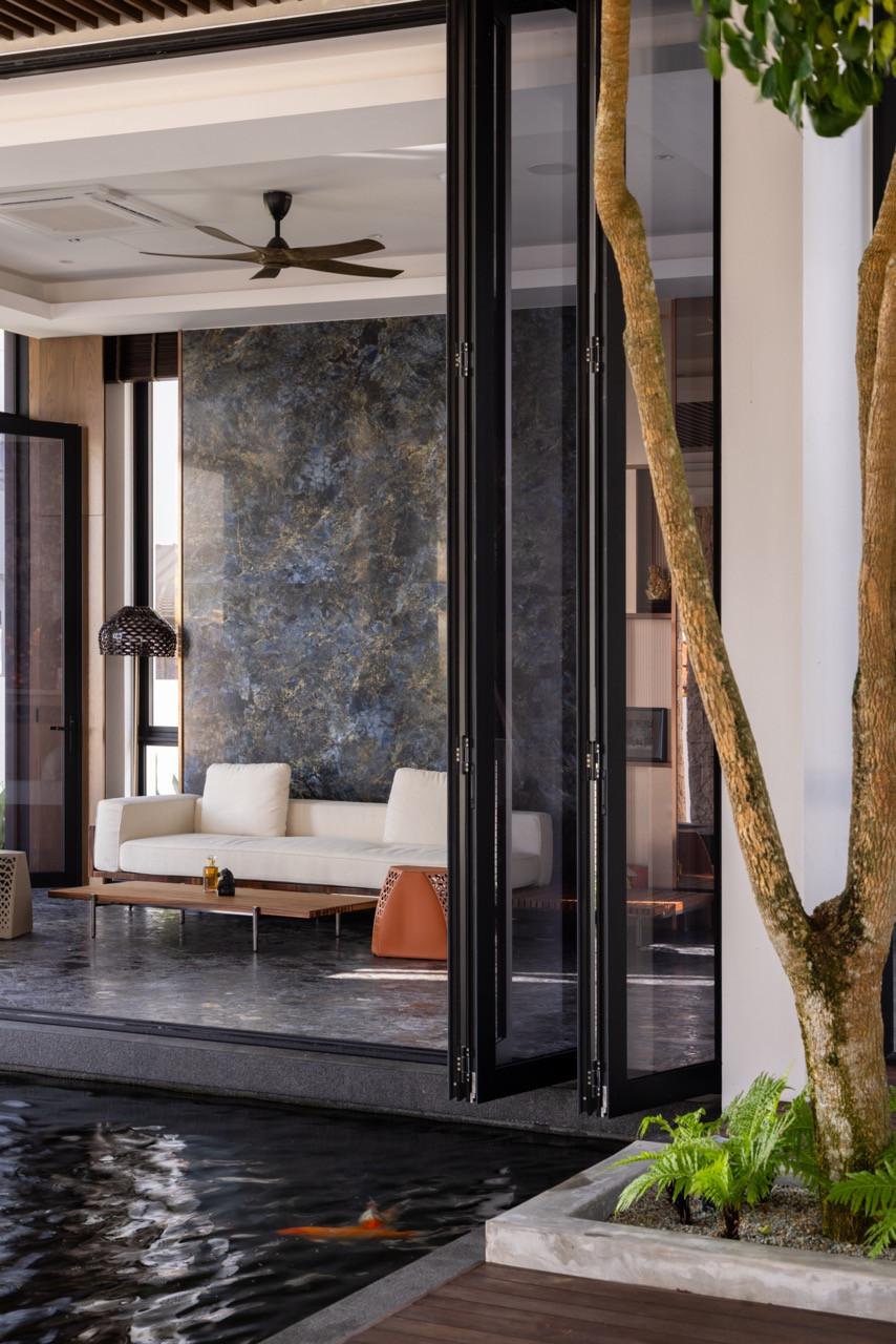 The koi pond at the threshold between the main house and the rear villa, viewed with the folding glass doors open