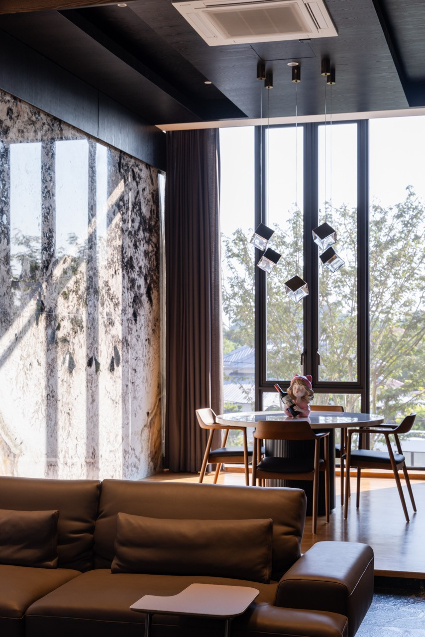 Morning light enters the dining area through floor-to-ceiling black-framed windows overlooking the neighbourhood