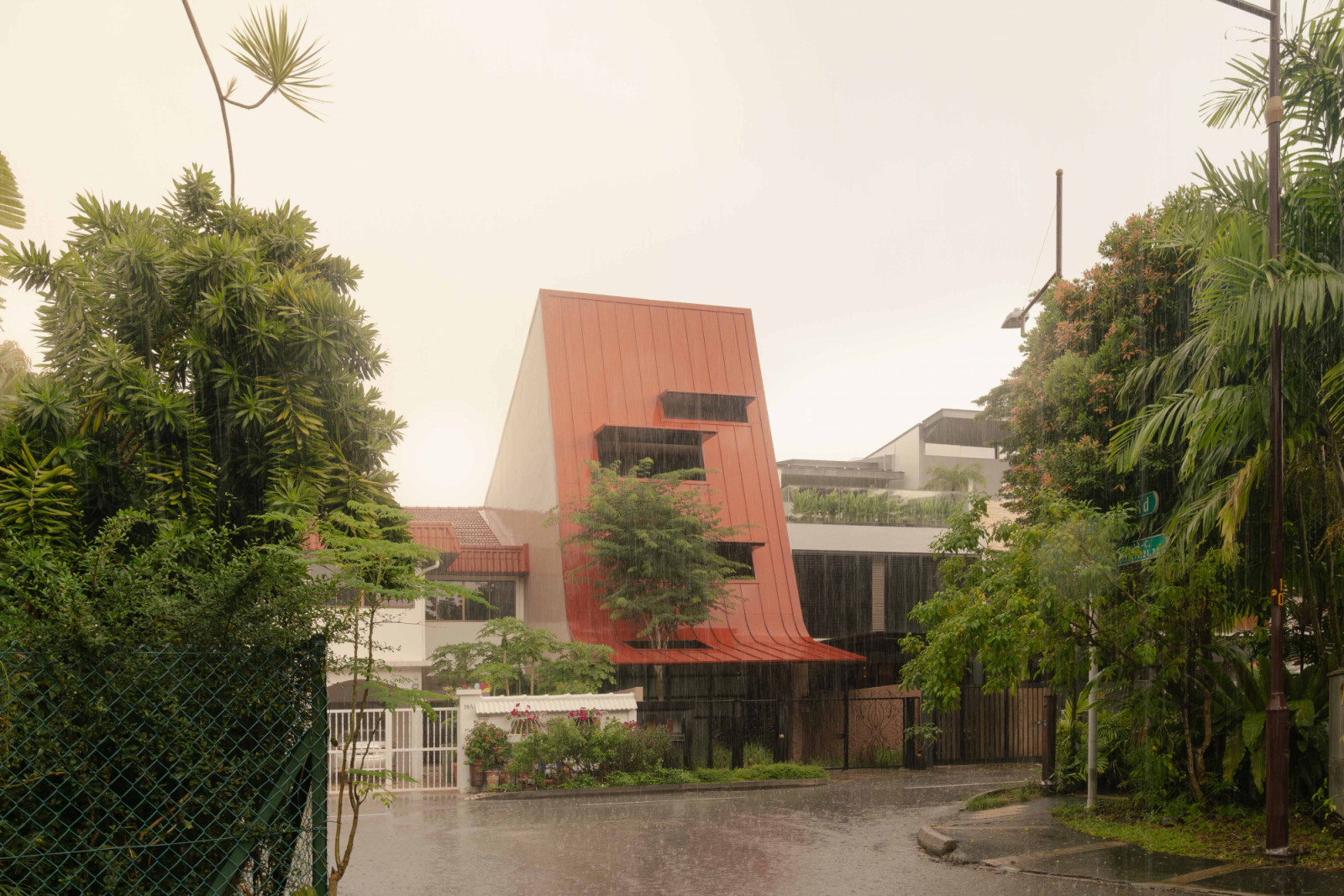 A moody view of the Giant Roof House on a rainy afternoon, its ribbed metal surface deepening in tone under the overcast sky