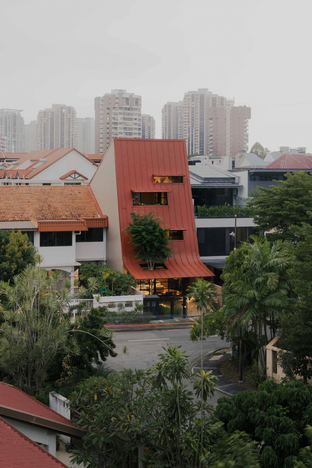 The terracotta giant roof cuts a distinct silhouette in the neighbourhood, its bold form setting the house apart from its more conventional surroundings in Singapore’s east