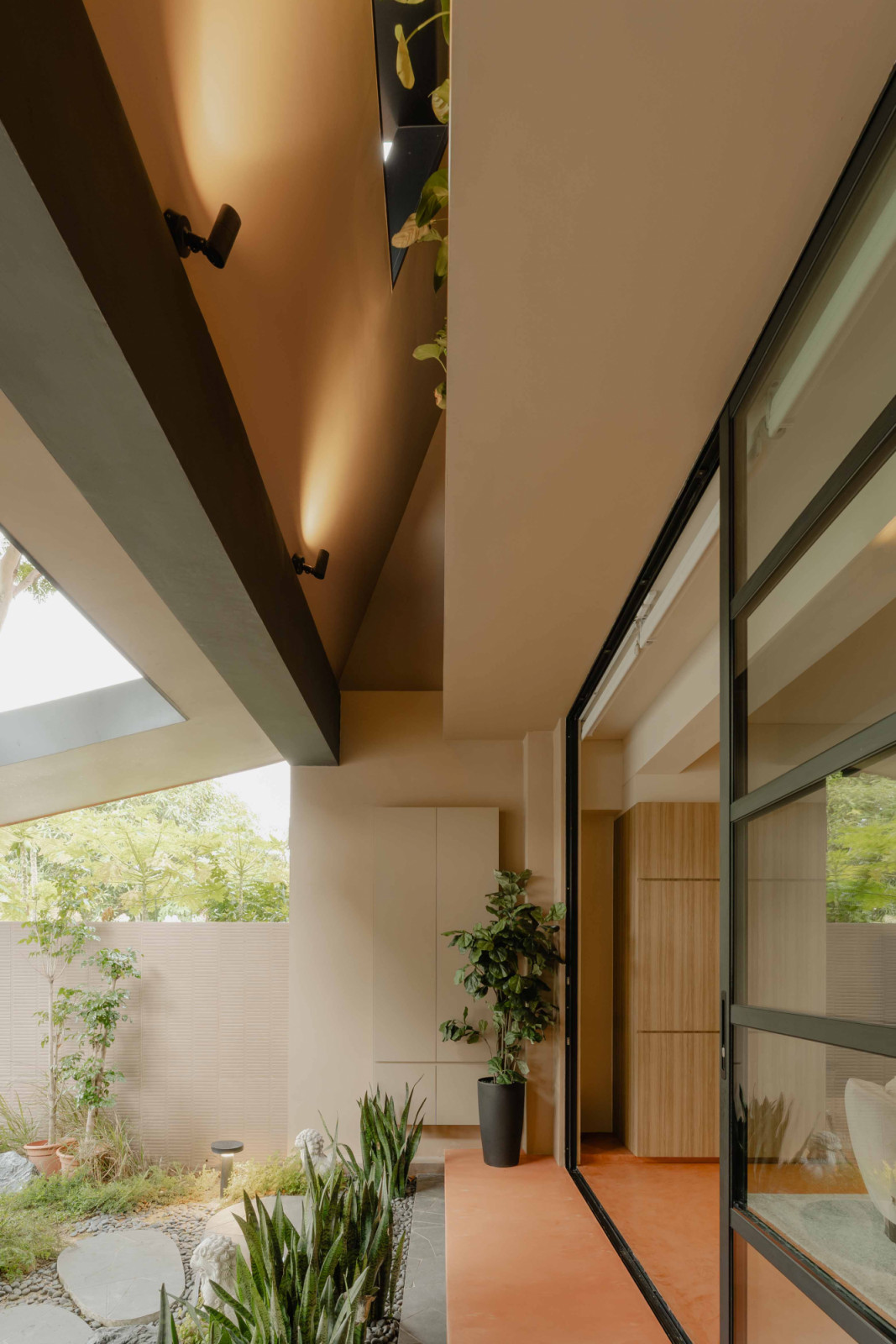 A glass entrance door is seamlessly integrated into full-width black steel glazing across the living room façade