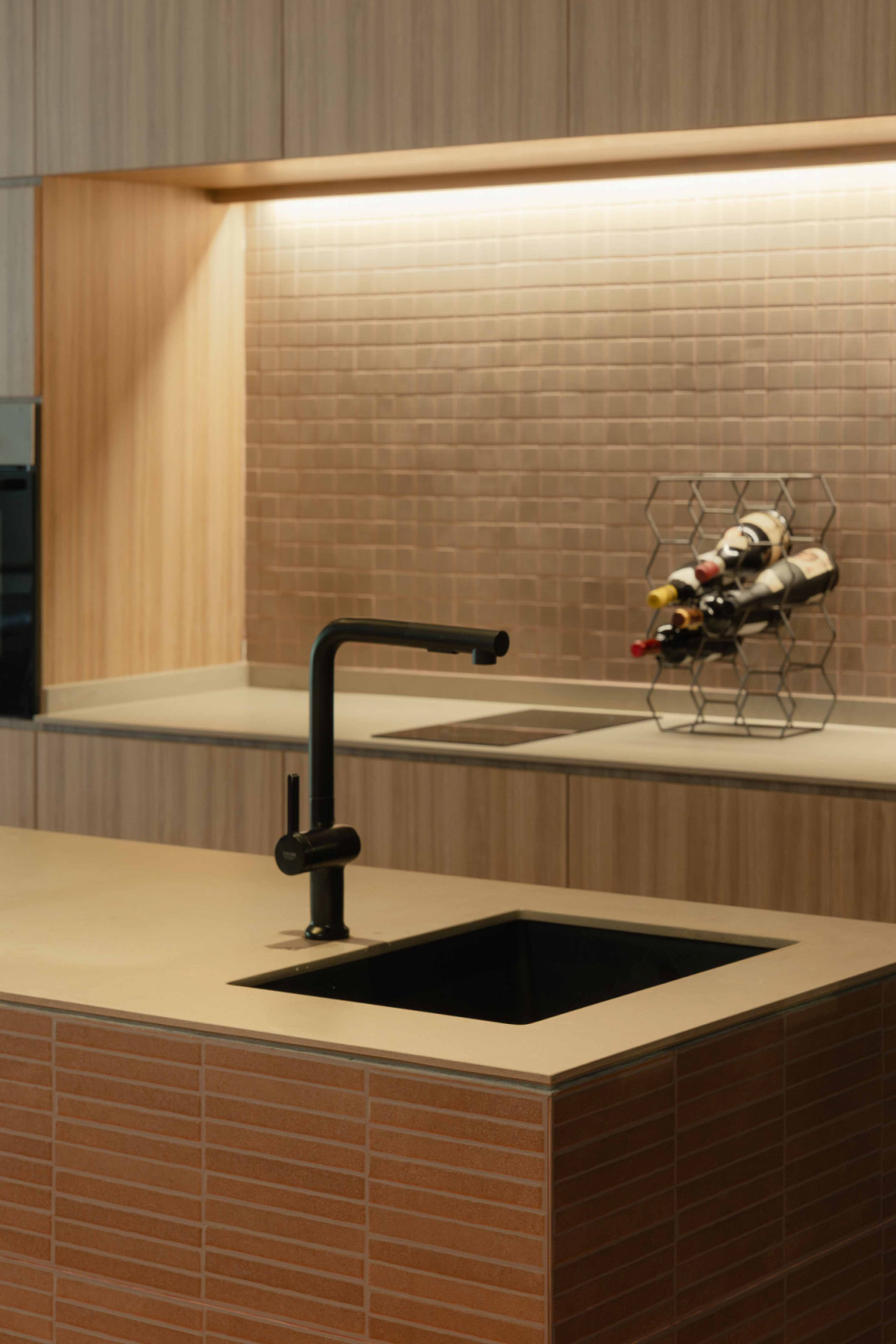 A brick-finished kitchen island grounds the dry kitchen, introducing material tactility against the home’s terracotta-toned palette