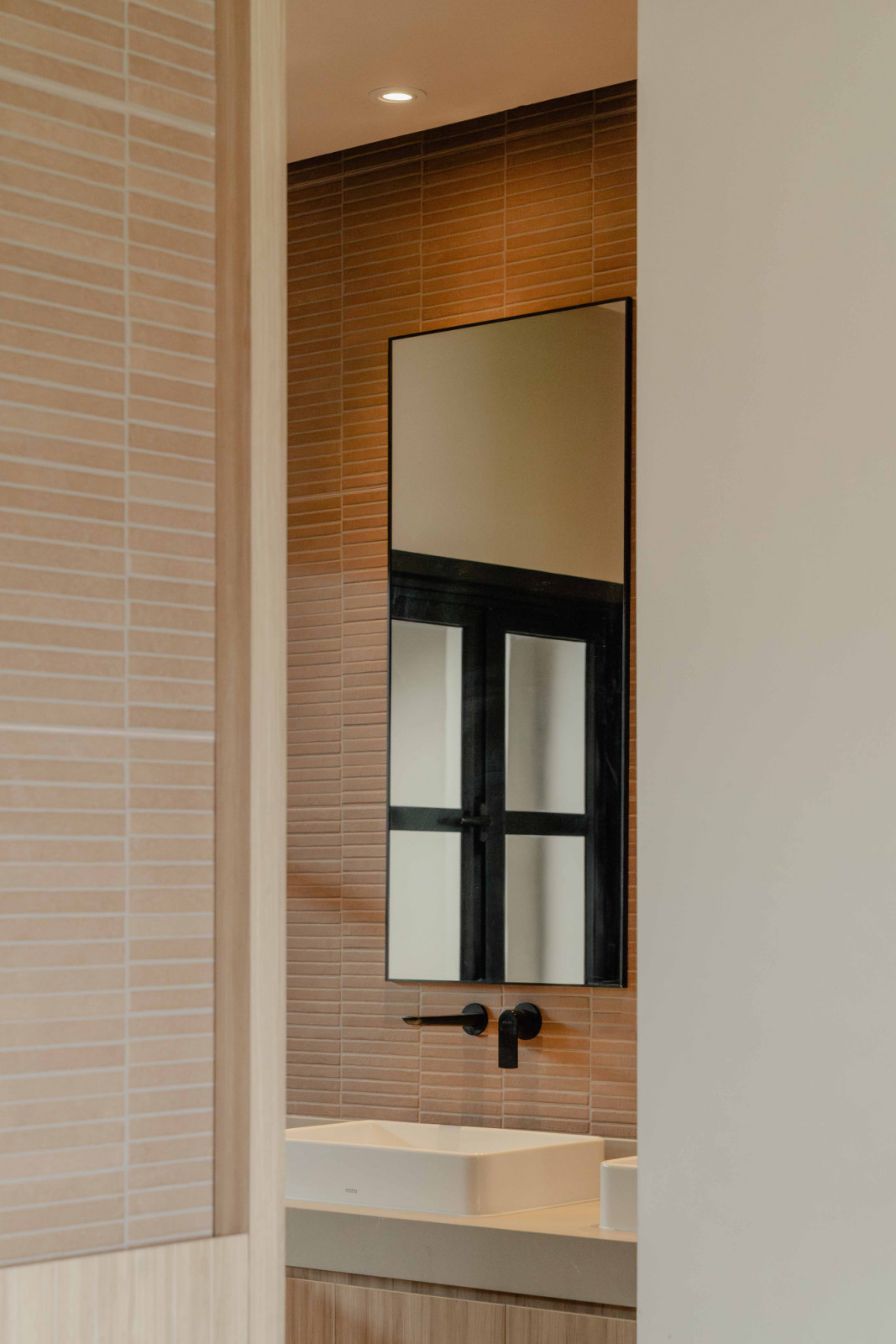 A glimpse of the bathroom reveals pale brick finishes that lend softness and texture to the compact space