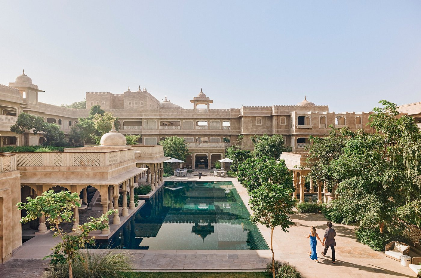 The resort’s main pool sits within the historic fort walls; the crenellated parapets and domed pavilions of the upper palaces are visible beyond