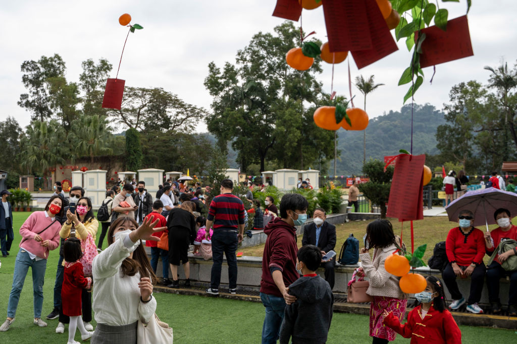 People trying to throw fake orange with a piece of paper with a wish written on it to Tsuen Wishing Tree on January 22, 2023 in Hong Kong, China. Hong Kong celebrates the Lunar New Years or Chinese New Years Holiday. (Photo by Vernon Yuen/NurPhoto via Getty Images)