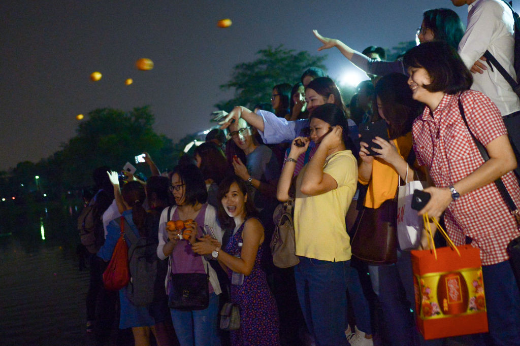KUALA LUMPUR, MALAYSIA - 2018/03/02: Malaysian ethnic Chinese women gather at a park as they throw mandarin orange written with their wishes and phone number into the lake, marking the end of Chinese New Year celebrations in Kuala Lumpur March 2, 2018. Chap Goh Mei is celebrated on the 15th night of Chinese New Year which symbolizes the end of Chinese New Year celebration, also known as Oriental's Valentine Day. It is celebrated with offerings and prayers while young unmarried women will throw a mandarin or