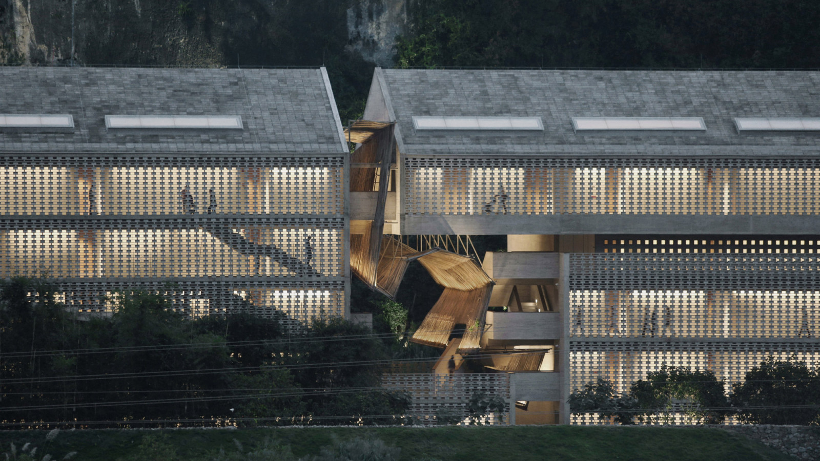 An aerial view of the new guest room wing designed by Vector Architects, its perforated hollow concrete block facade filtering light from within; a sculptural bamboo installation marks the entrance between the two volumes
