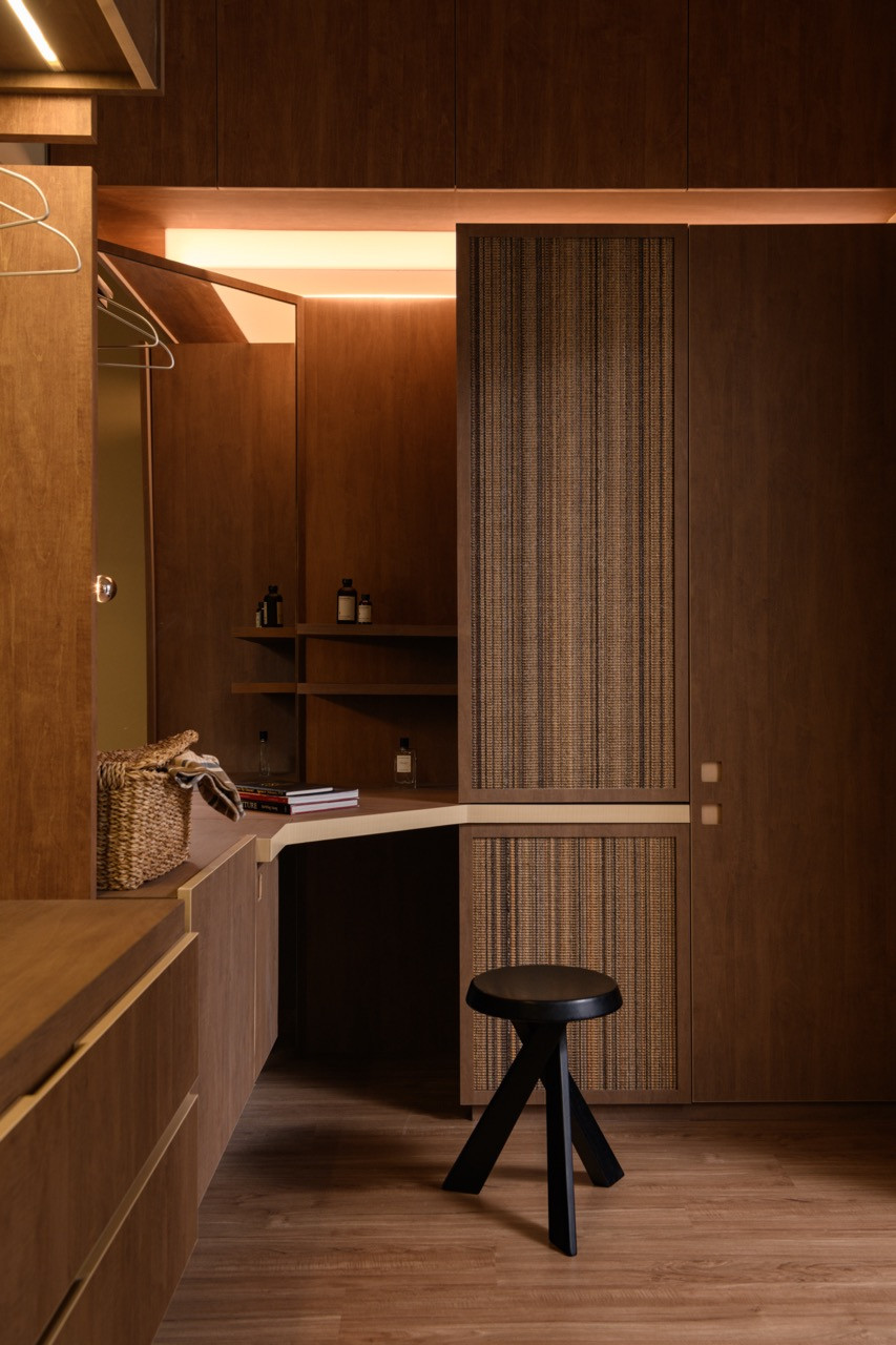 The master bedroom dressing area features dark wood cabinetry with textured woven panel doors, a curved countertop, and warm strip lighting recessed into the ceiling