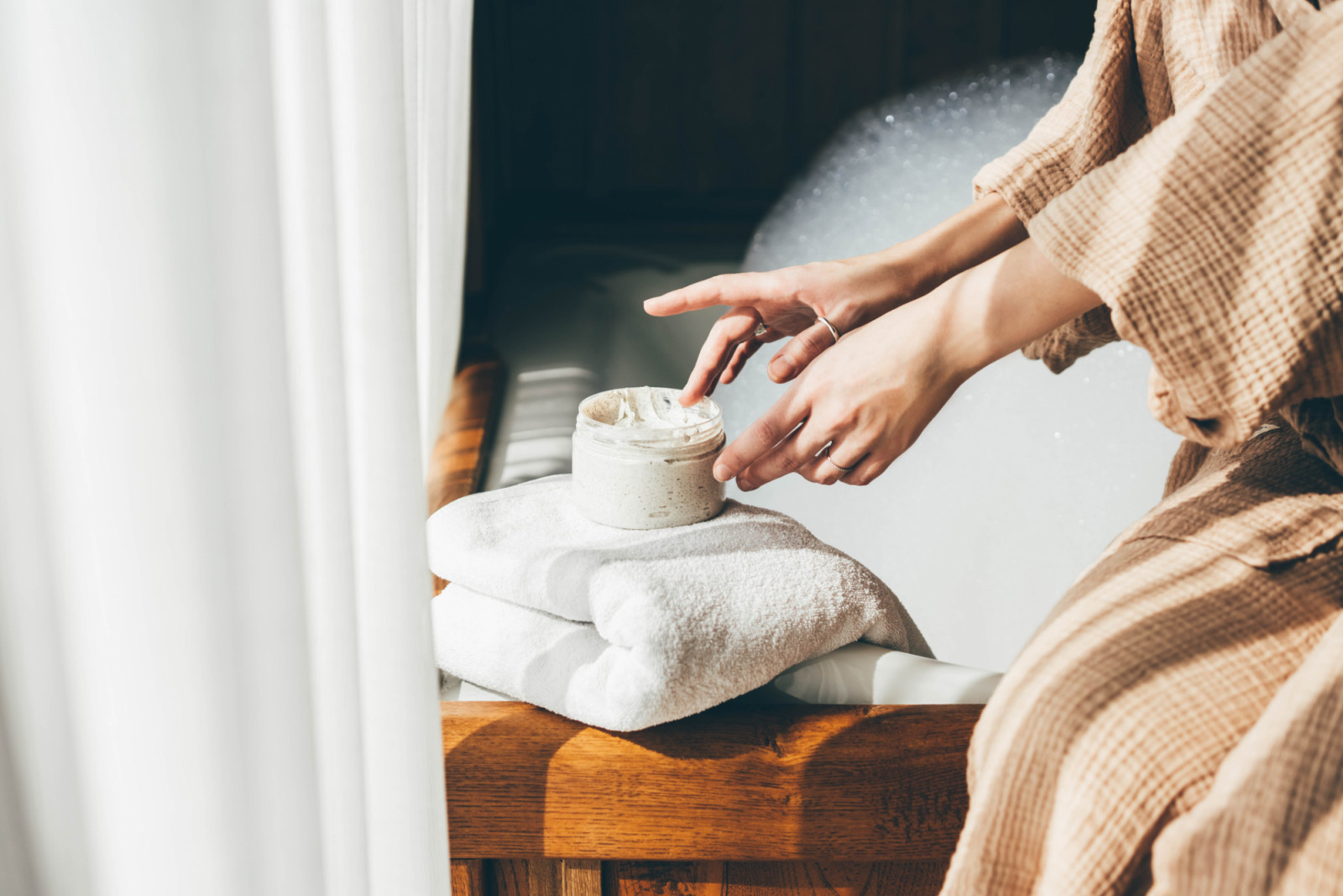 Woman taking care of her skin. Young woman in bathroom applying cream.