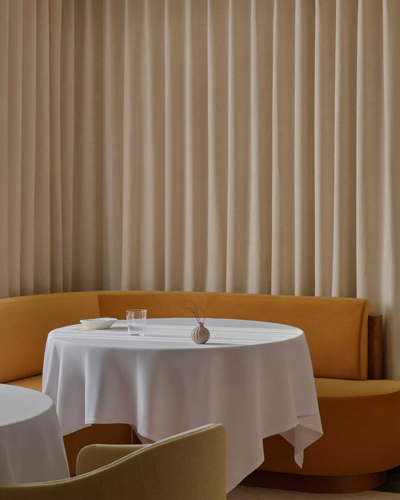The refreshed private dining room at Odette, with its amber curved banquette and floor-to-ceiling linen curtains (Photo: Odette)