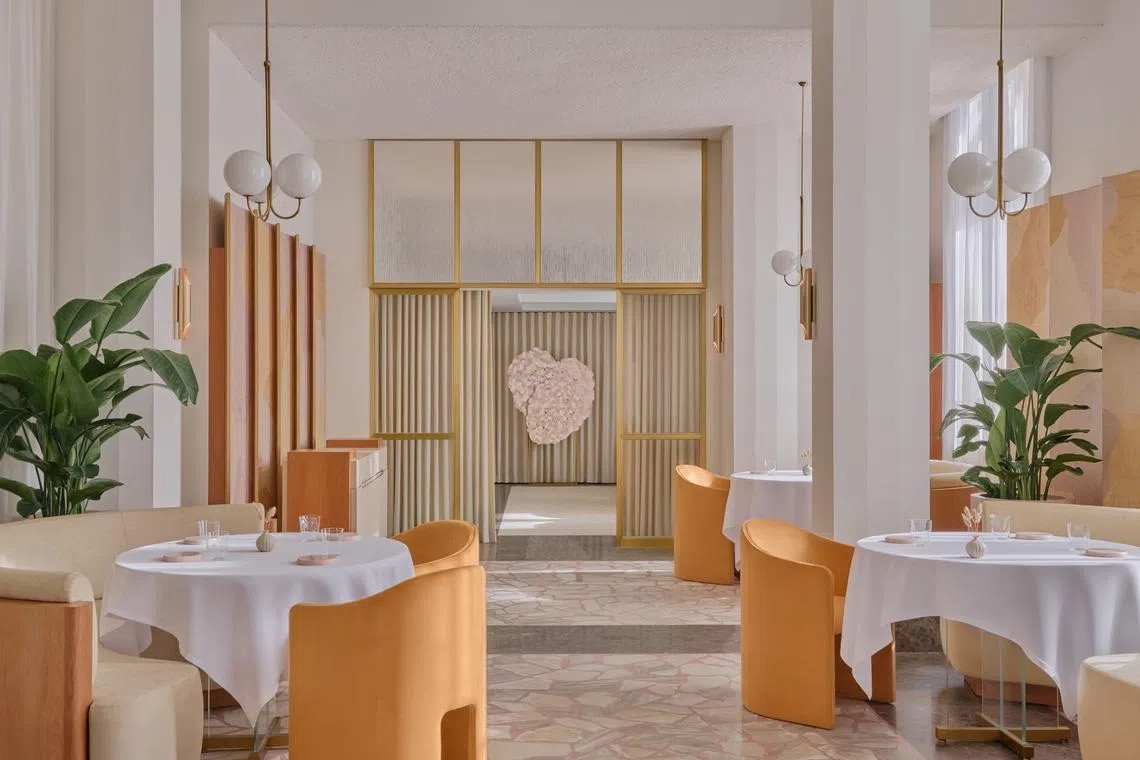 The main dining room of Odette following its 2025 renovation, with terrazzo flooring, amber upholstery and a Dawn Ng artwork visible through the gold-framed glass partition (Photo: Odette)